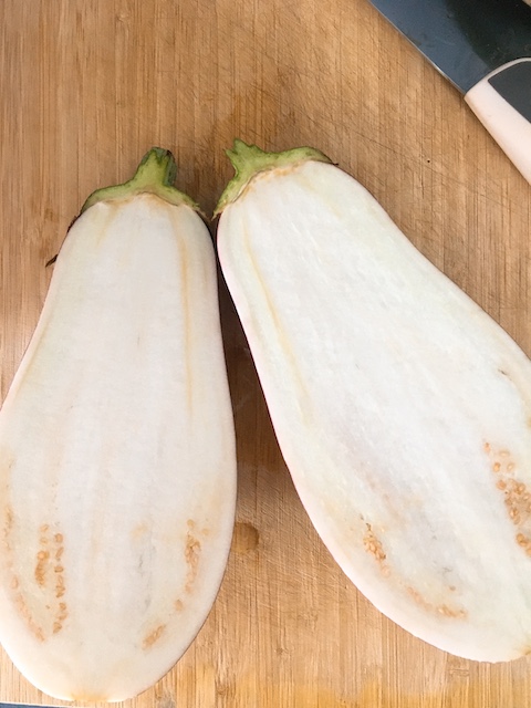 A grafitti eggplant/aubergine cut into half.