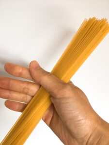 Measuring 80 g pasta with hand.