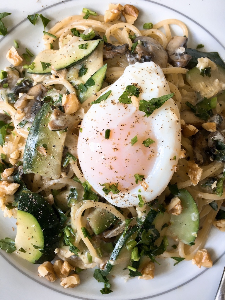 A poached egg on top of a plate of creamy pasta.