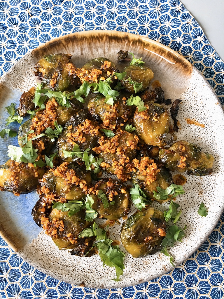 A plate of roasted and smashed Brussels sprouts with fragrant garlic oil.