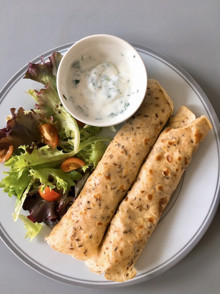 Indian aloo masala kathi roll with yogurt dipping sauce and salad.