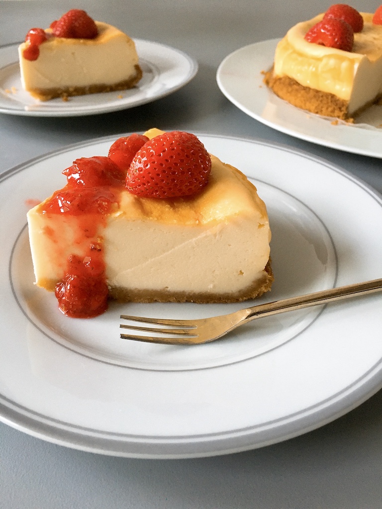 A piece of baked cheesecake with fresh strawberry sauce.