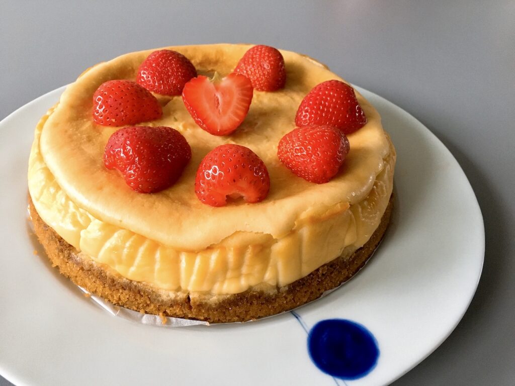 A whole of baked cheesecake with fresh strawberry sauce.