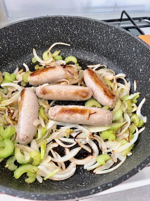 Pan-searing sausages, celery and onions until browned.