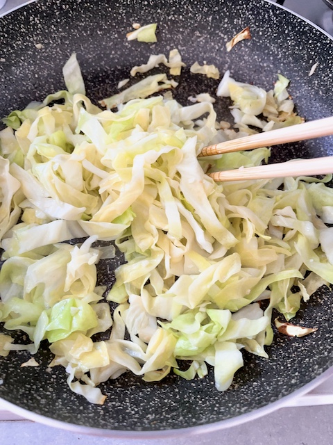 Use chopsticks to stir-fry cabbage until wilted.