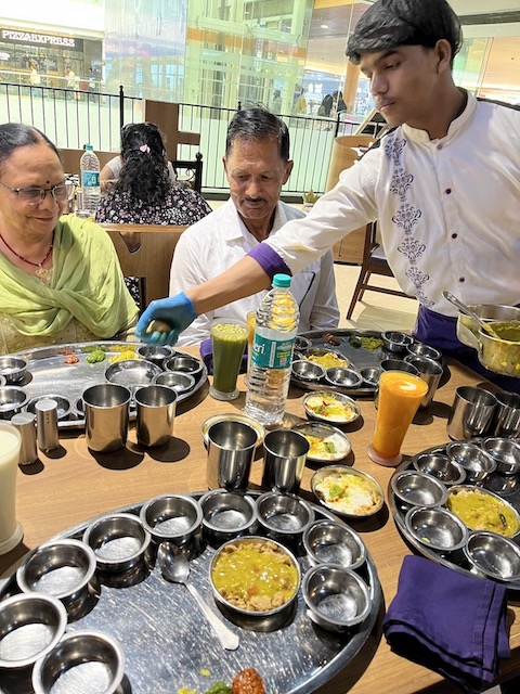 A server brings food to fill the thali. 