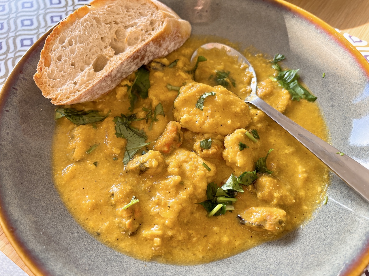 Fruity almond curry sauce with seafood, paired with baguette.