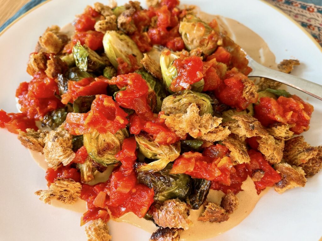 Roast Brussels sprouts with spicy tomato sauce and croutons.