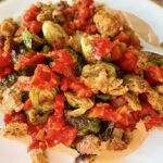 Roast Brussels sprouts with spicy tomato sauce and croutons.