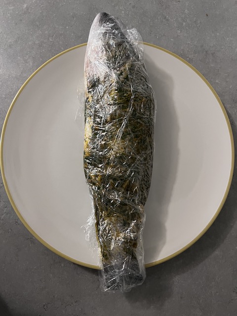 Whole sea bass marinated with chermoula and wrapped in cling film.