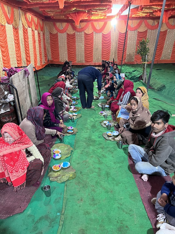 Guests sitting on the ground in an Indian wedding.