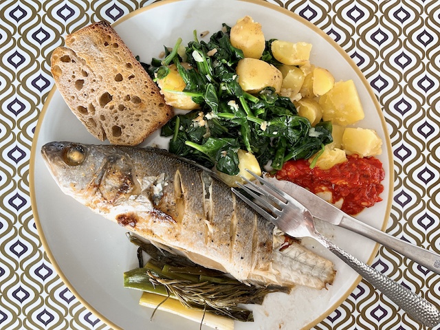 Baked whole sea bass with spinach and potatoes, harissa sauce and crusty bread.