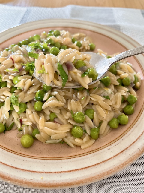 A spoonful of orzo with peas.