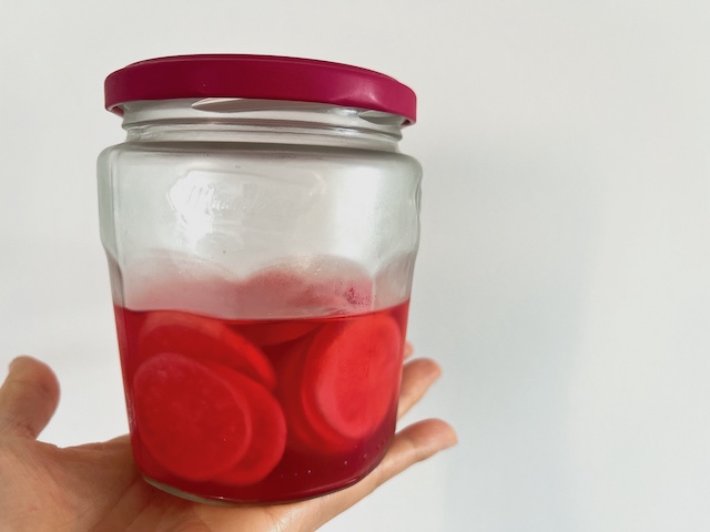 A half jam jar of radish pickles.