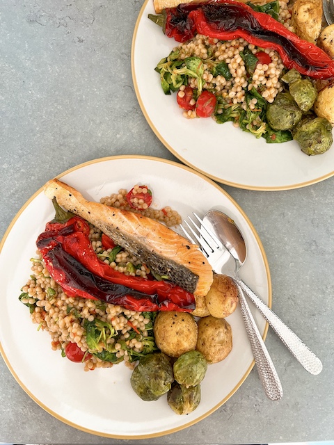 Two plates of pan-seared salmon with roasted Romano pepper, paired with giant couscous.